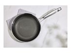 Overhead view of a non-stick frying pan with a honeycomb pattern on a white marble surface.