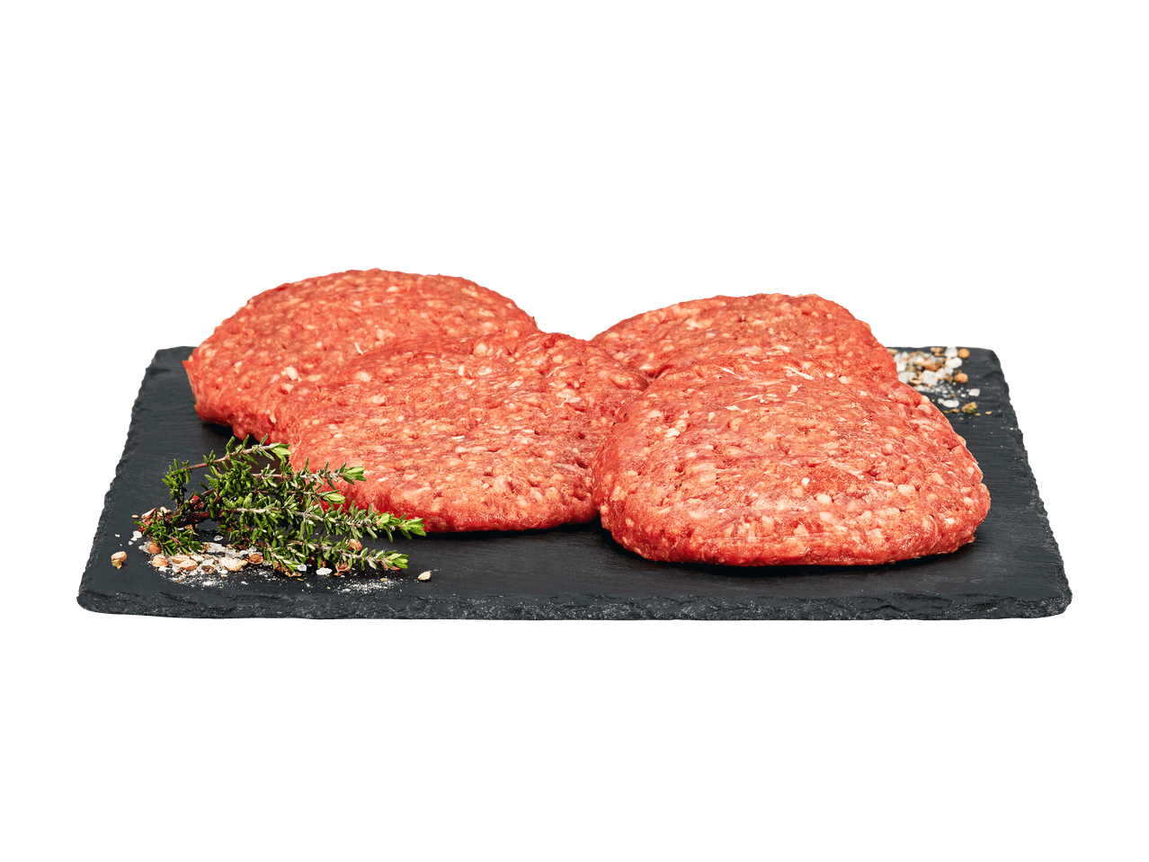 Vier rohe Burger-Patties auf einem Schieferbrett mit Thymian und Gewürzen.