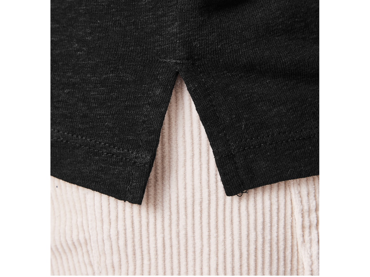 Pulover negru tricotat peste pantaloni de catifea coardată bej.