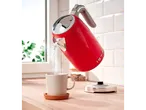 Silvercrest® red kettle pouring water into a mug on a wooden counter