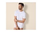 Man in white t-shirt and underwear, smiling and looking to the side.