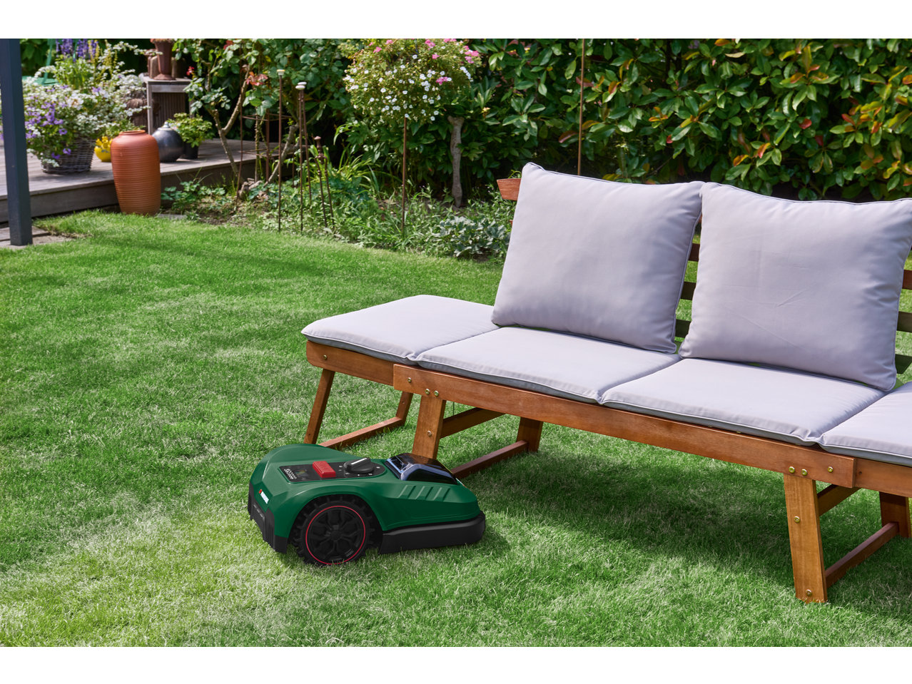 PARKSIDE smart robotic lawnmower in the garden with a wooden bench.