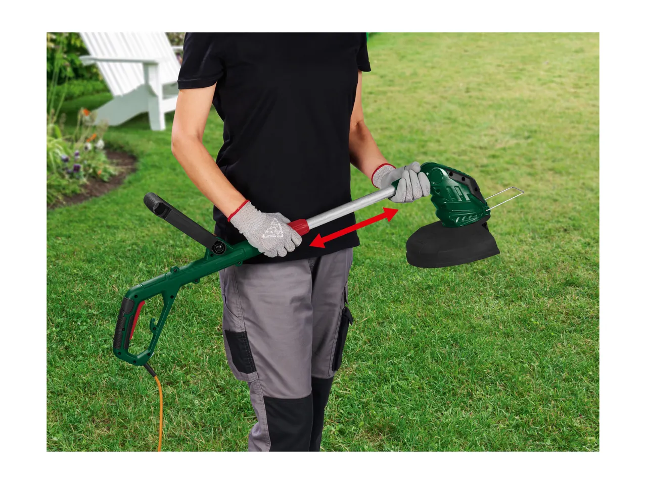 Person in work gloves holding a green and black electric grass trimmer with an orange cord.