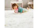 Toddler drinking from a sippy cup on a white rug.