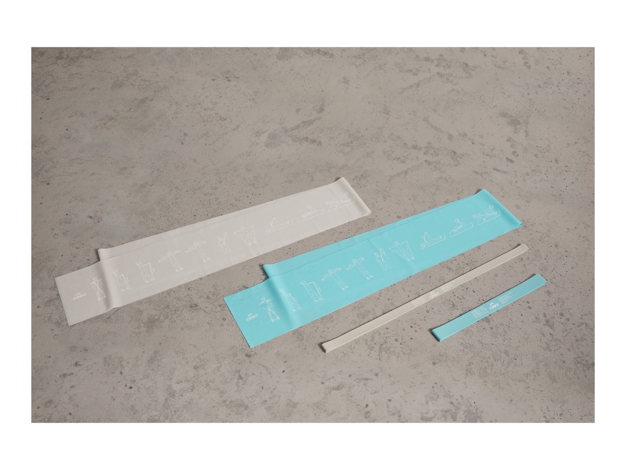 Two resistance bands with exercise illustrations and two smaller bands on a concrete surface.