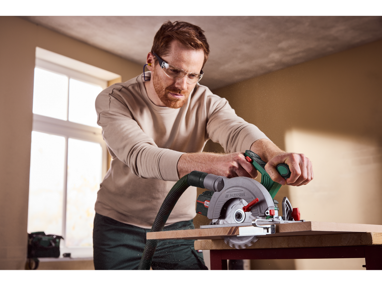 Mann benutzt eine Parkside 20 V Akku-Kreissäge zum Holzschneiden.
