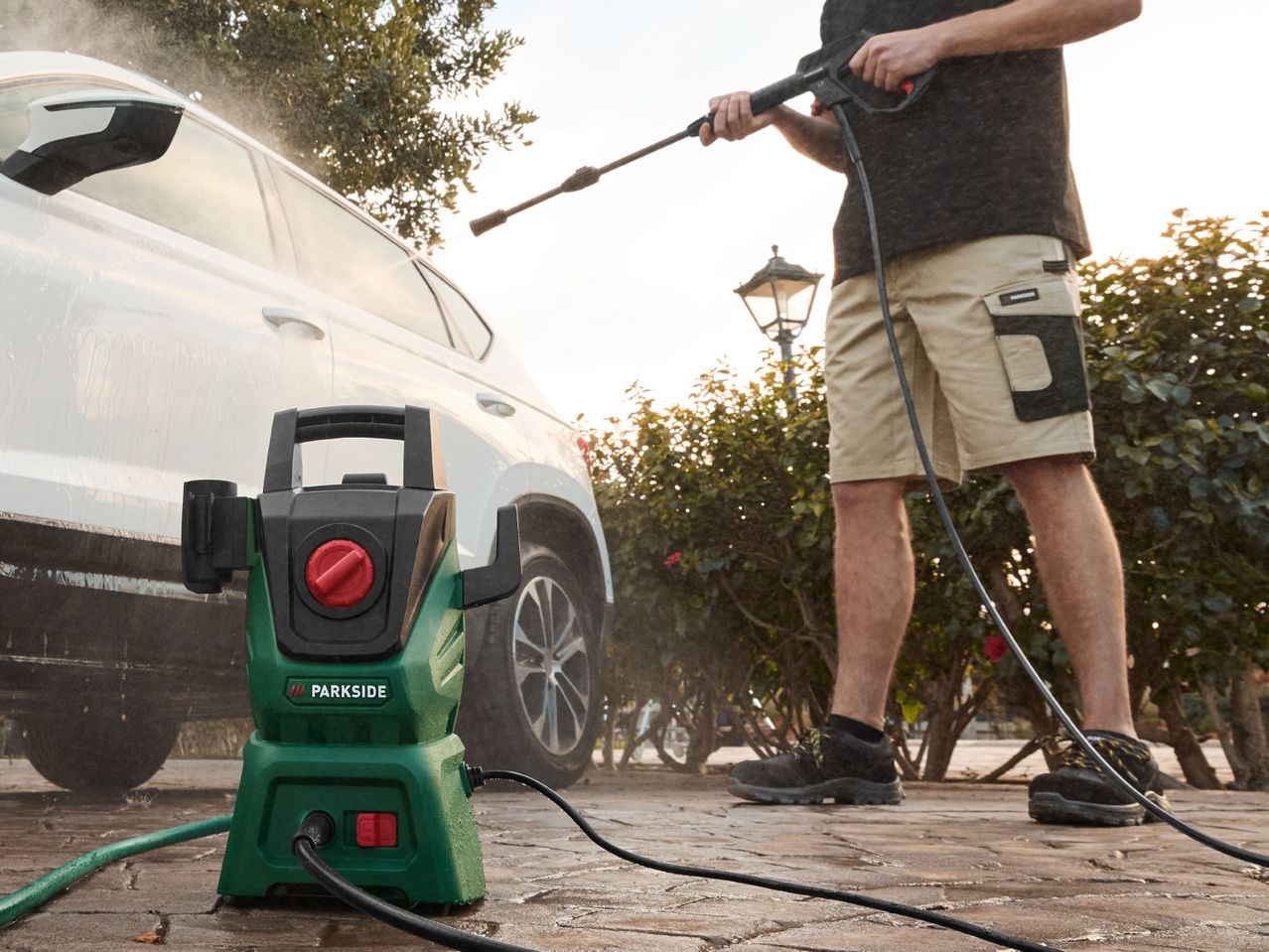 A man uses a Bosch electric pressure washer to clean his car.