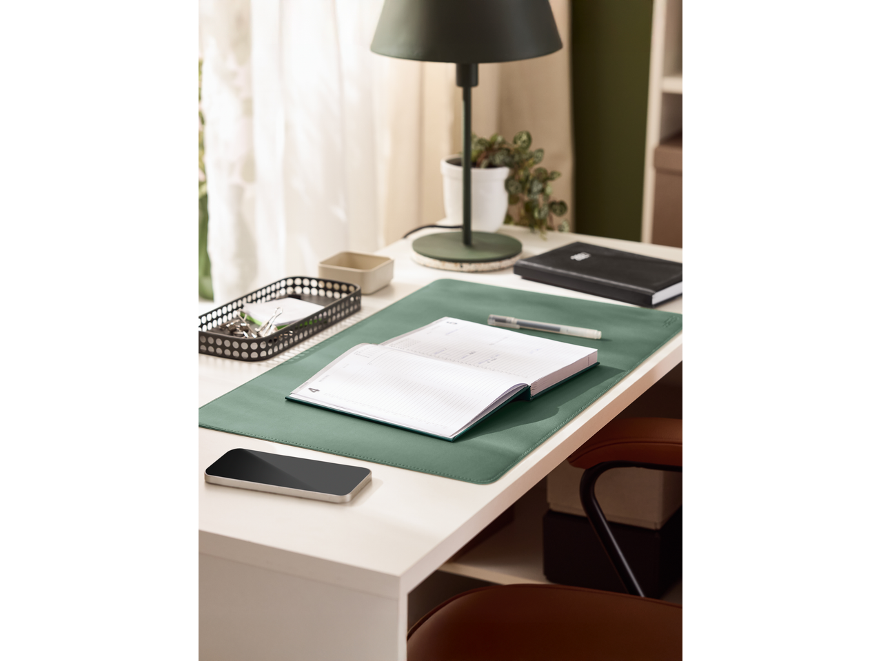 Crelando Planner on a green desk mat with a pen, phone, and desk lamp.