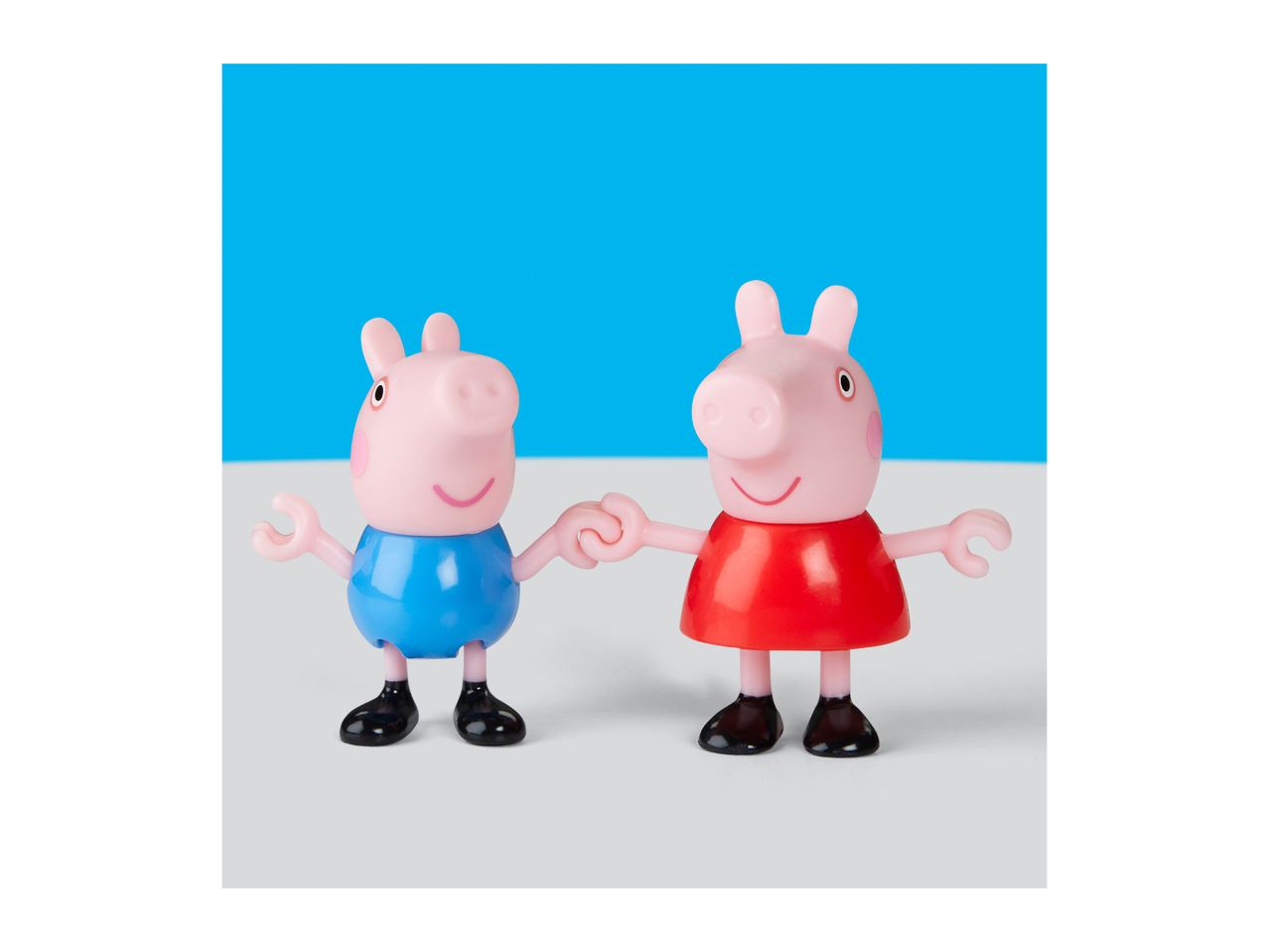 Two pig figurines, one in a blue top and one in a red dress, holding hands.
