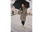 Woman in leopard print coat and boots holding an umbrella on stairs.