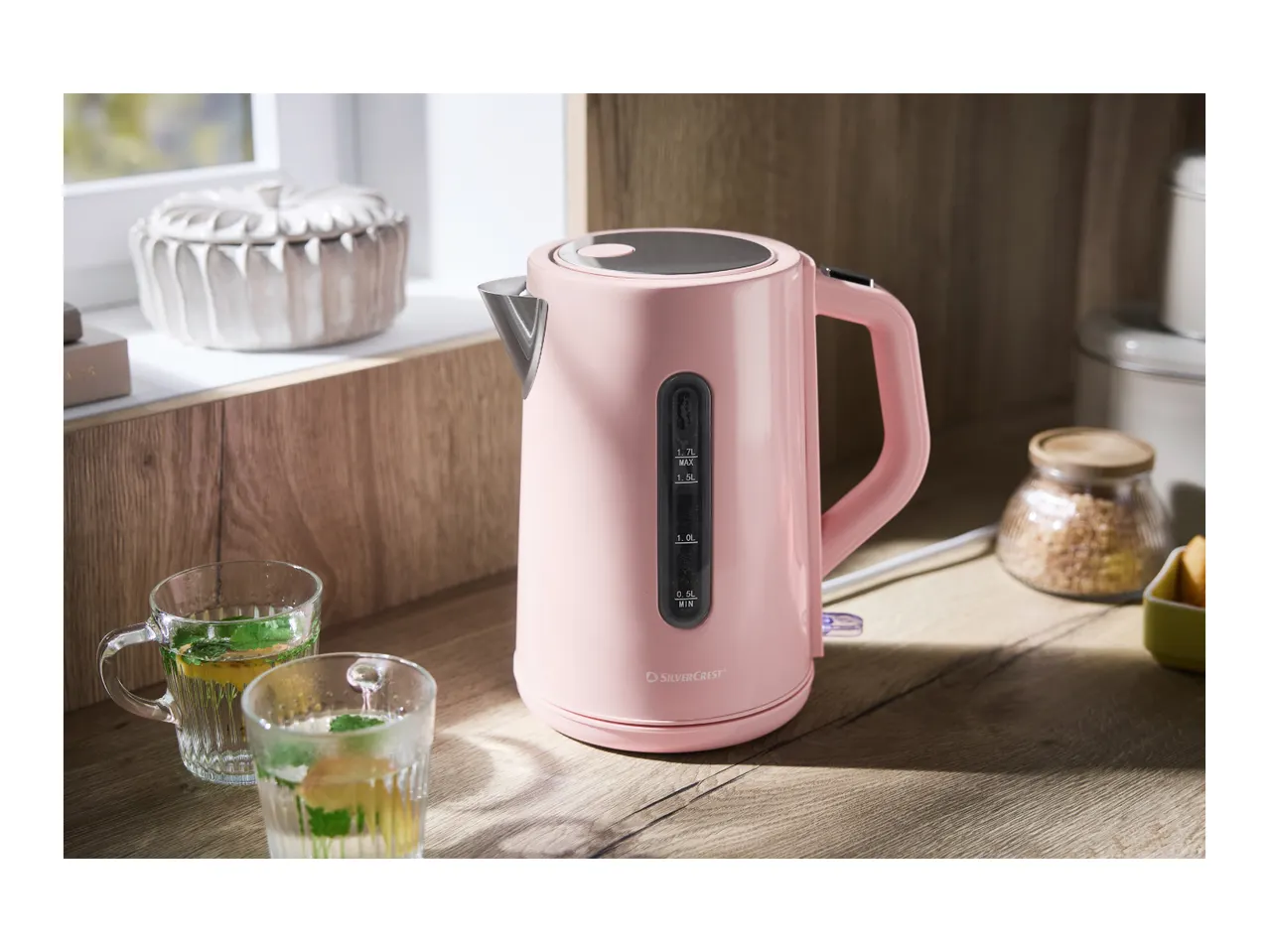 Pink electric kettle on a wooden counter with two glasses of iced tea.