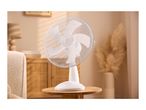 White table fan on a wooden side table in a cozy living room.