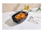 Roasting pan with a glass lid containing a roasted chicken on a kitchen counter