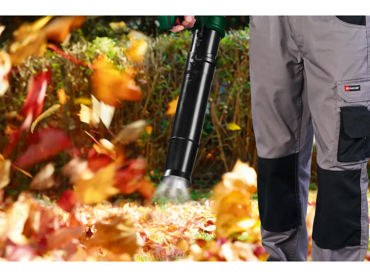 A man uses a leaf blower to clear fallen leaves.