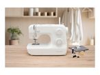 White sewing machine with accessories on a wooden table