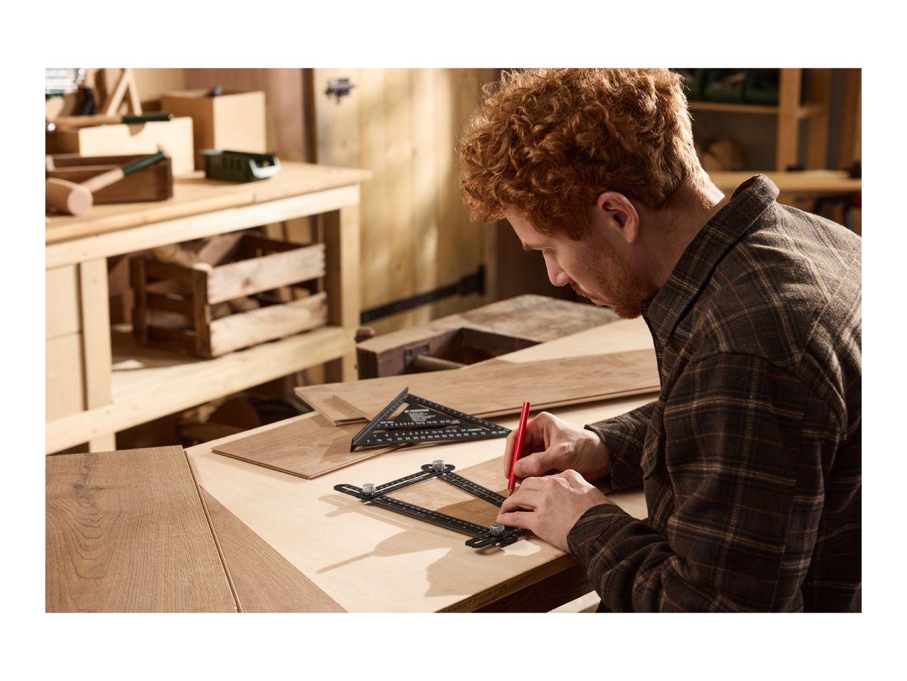 Man marking wood with a red pencil and measuring tools on a workbench.