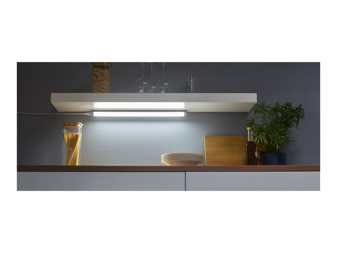 Kitchen shelf with LED light, pasta jars, wine glasses, and a plant.