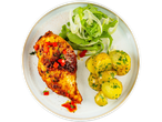 Grilled chicken breast with roasted potatoes and a fresh salad on a white plate.