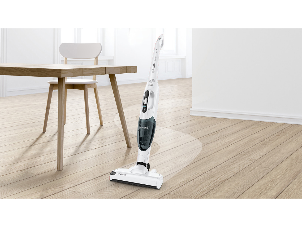 Beli 2 v 1 akumulatorski sesalnik v moderni sobi z lesenimi tlemi in mizo.