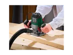 A man uses a Parkside POF 1200 E4 router to work wood.