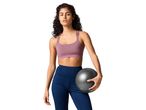 Woman in a sports bra and leggings holding a small exercise ball.