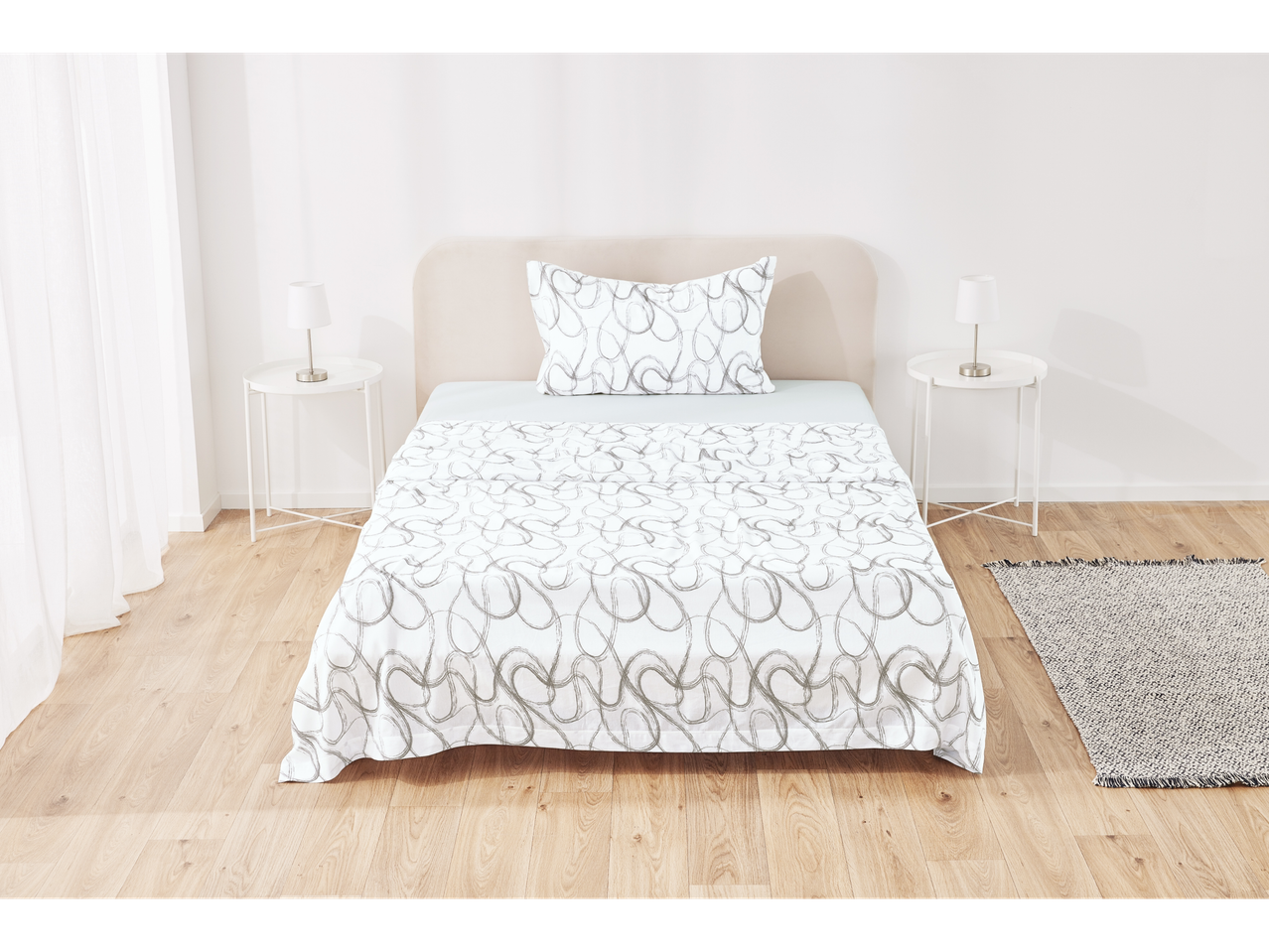 A bed with white sheets featuring a gray pattern, two nightstands, and a rug in a room.
