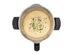 Overhead view of a stainless steel cooking pot with creamy sauce and herbs