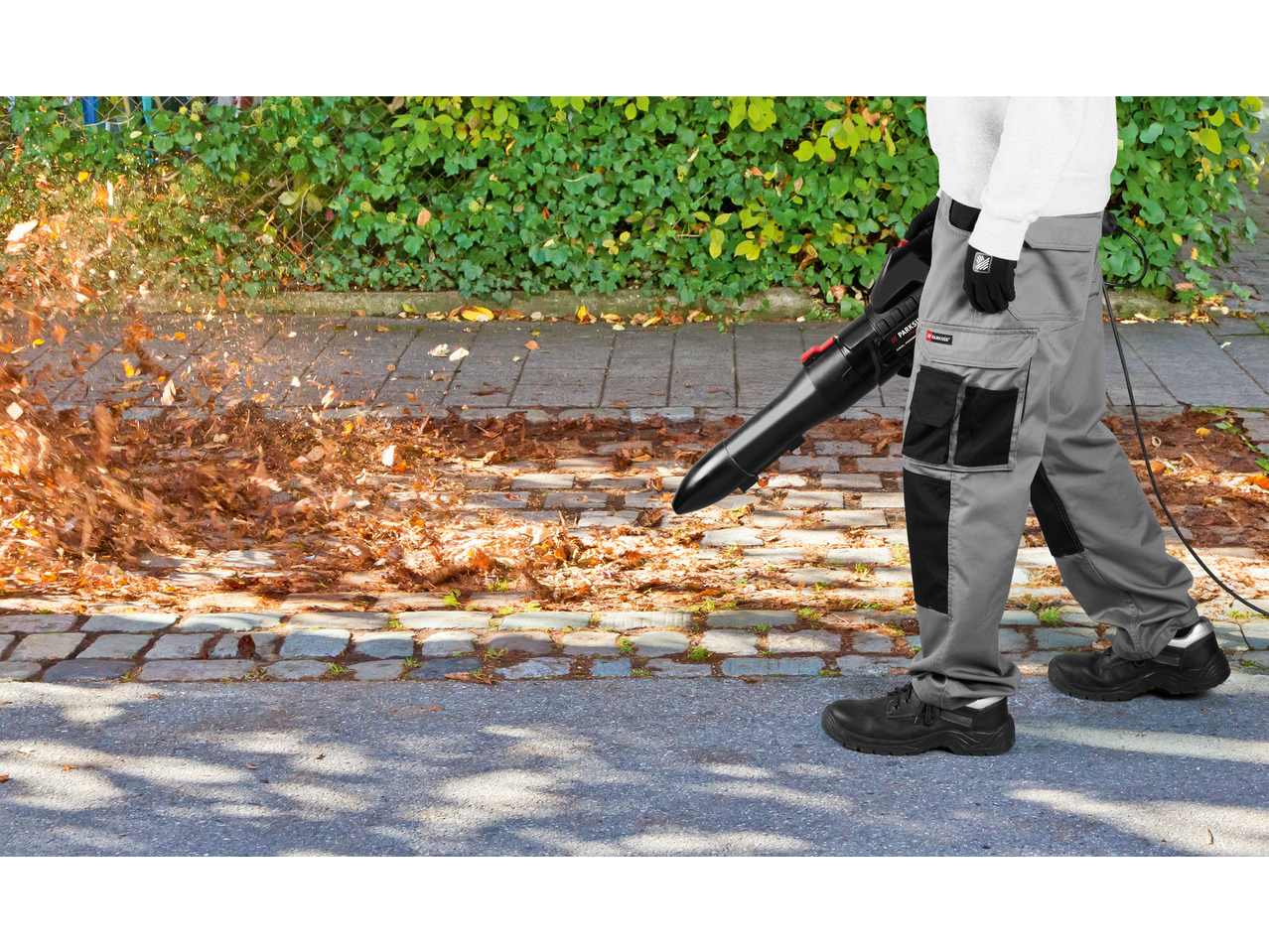 Muškarac koristi PARKSIDE PERFORMANCE duvač lišća za čišćenje trotoara.