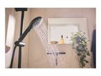 Black shower head spraying water in a modern bathroom with a mirror and plant.