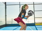 Mulher de t-shirt preta e saia-calção bordeaux a jogar padel com uma raquete.