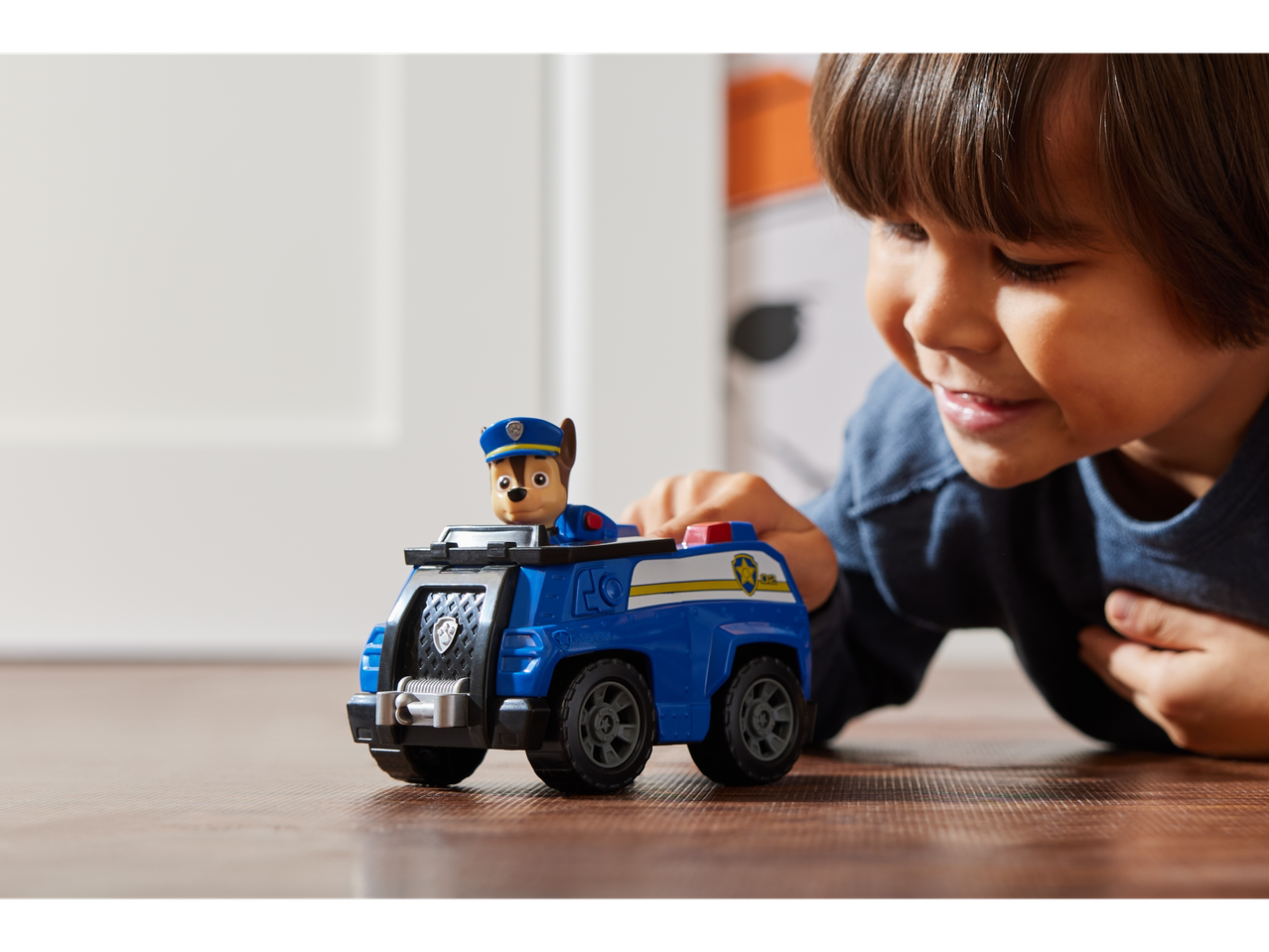 Enfant jouant avec la figurine et le véhicule PAW PATROL Chase sur le sol.