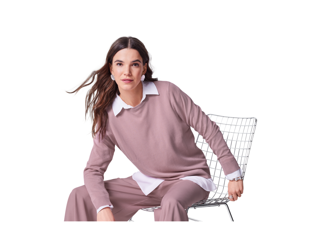 Naine Esmara roosas kampsunis ja sobivates pükstes, istumas toolil.