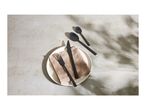 Black cutlery set with a plate and napkin on a concrete surface with shadows.
