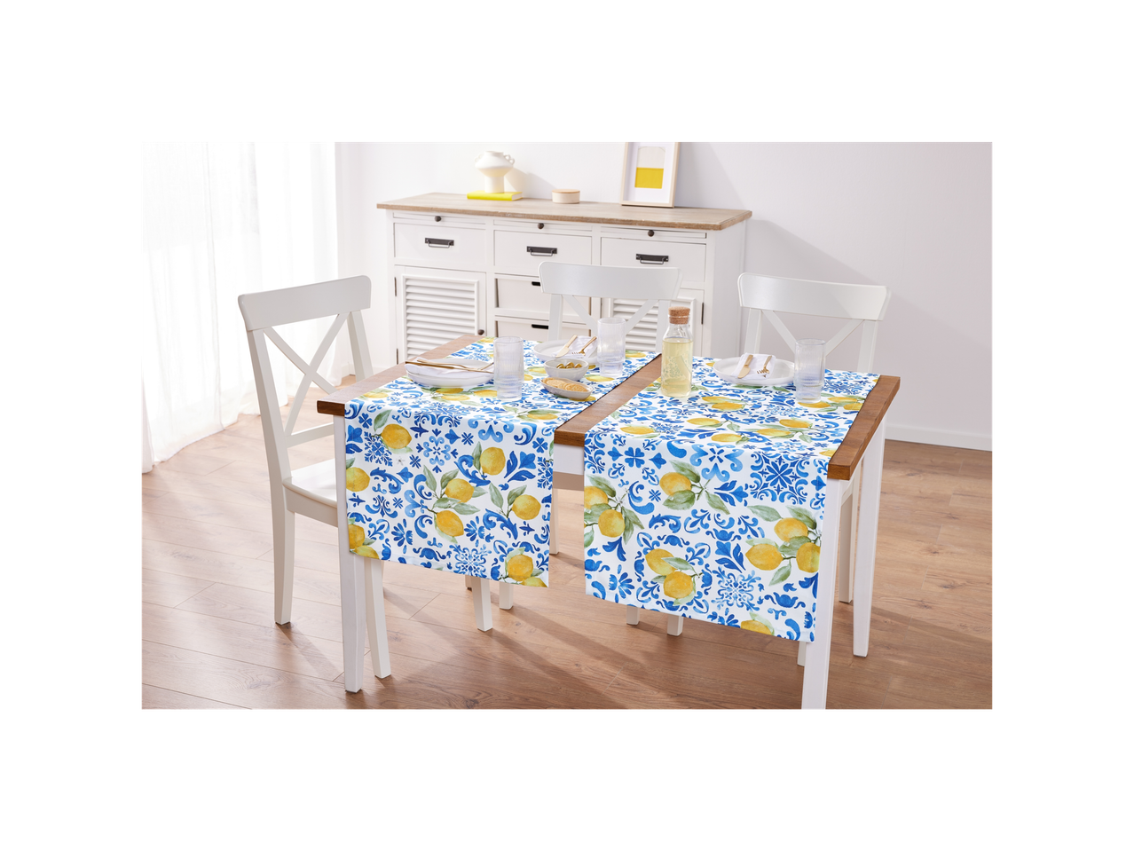 Two lemon-patterned table runners adorn a white dining table with chairs.