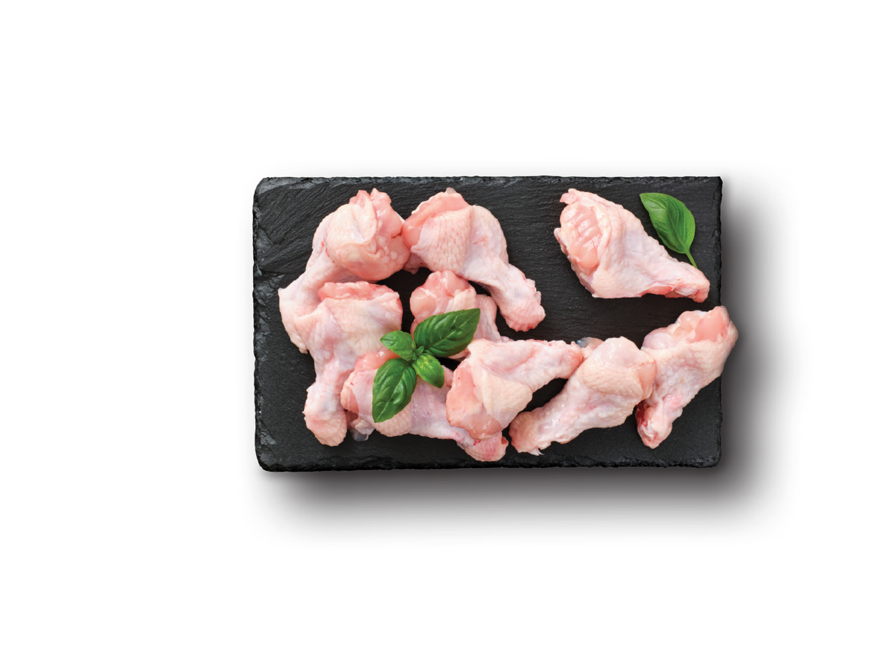 Jēli vistas spārniņi un baziliks uz melna akmens dēlīša.