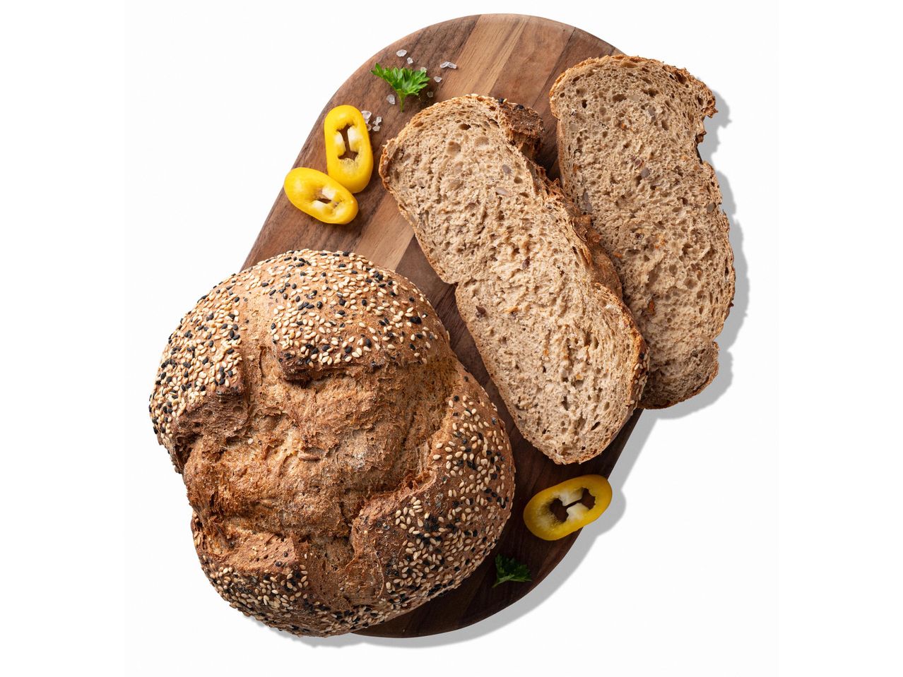 Teljes kiőrlésű kenyér szezámmaggal és szeletelt kenyér egy fa vágódeszkán, paprikával és sóval.