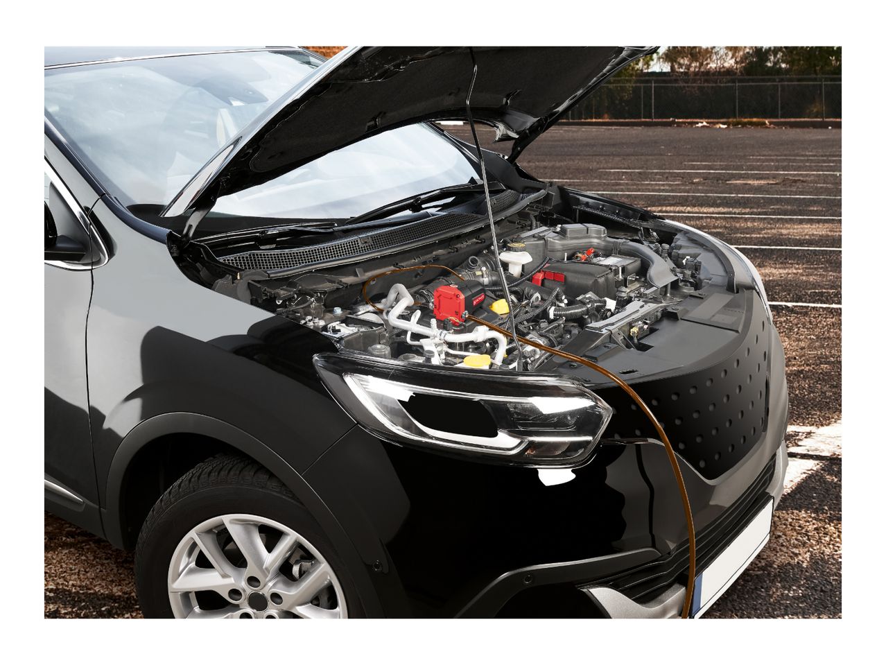 An electric oil extractor pump connected to a car engine under an open hood.