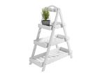 White wooden plant stand with three shelves, holding a potted rosemary plant.