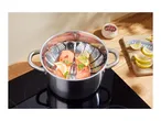 Salmon fillets with lemon and herbs in a steamer basket inside a pot on an induction hob.