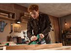 Man planing wood with an electric planer in a workshop.