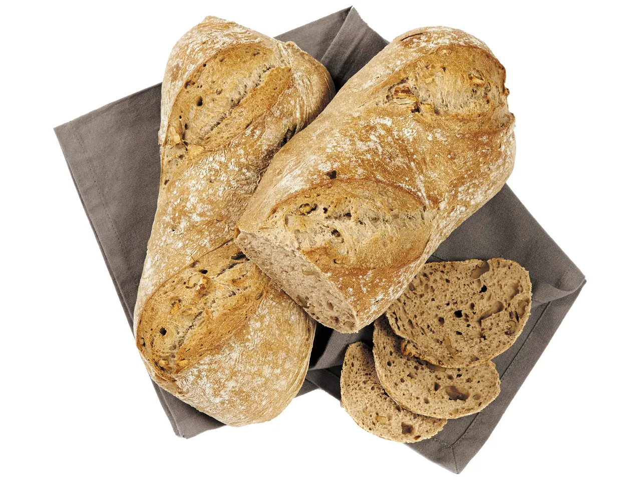 Deux pains aux noix et quelques tranches sur un torchon gris.