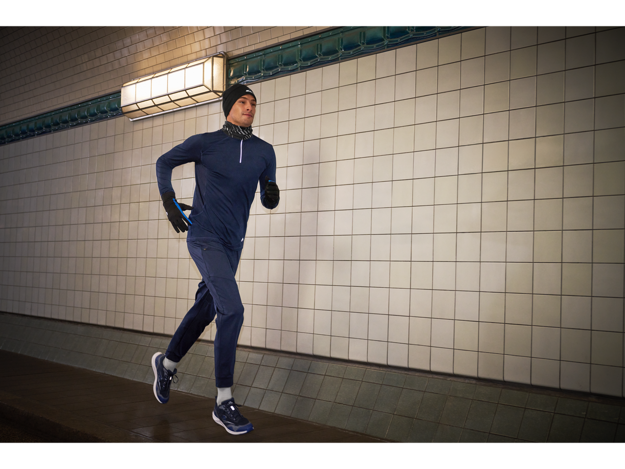 Bărbat alergând într-un tunel, purtând un tricou termic CRIVIT și echipament sportiv asortat.