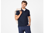 Bărbat zâmbitor purtând un tricou polo bleumarin și pantaloni, cu o jachetă bej pe umăr.