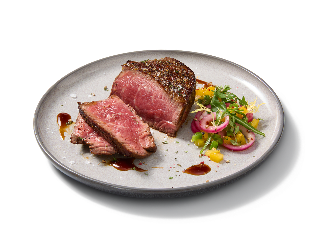 Steak de bœuf tranché avec une salade fraîche de légumes et d'oignons rouges.