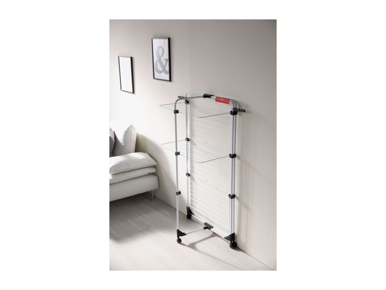 White clothes drying rack with multiple tiers in a modern living room setting.