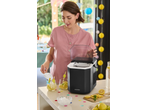 Woman using a SILVERCREST® Ice Maker to add ice to lemonade drinks at a party.