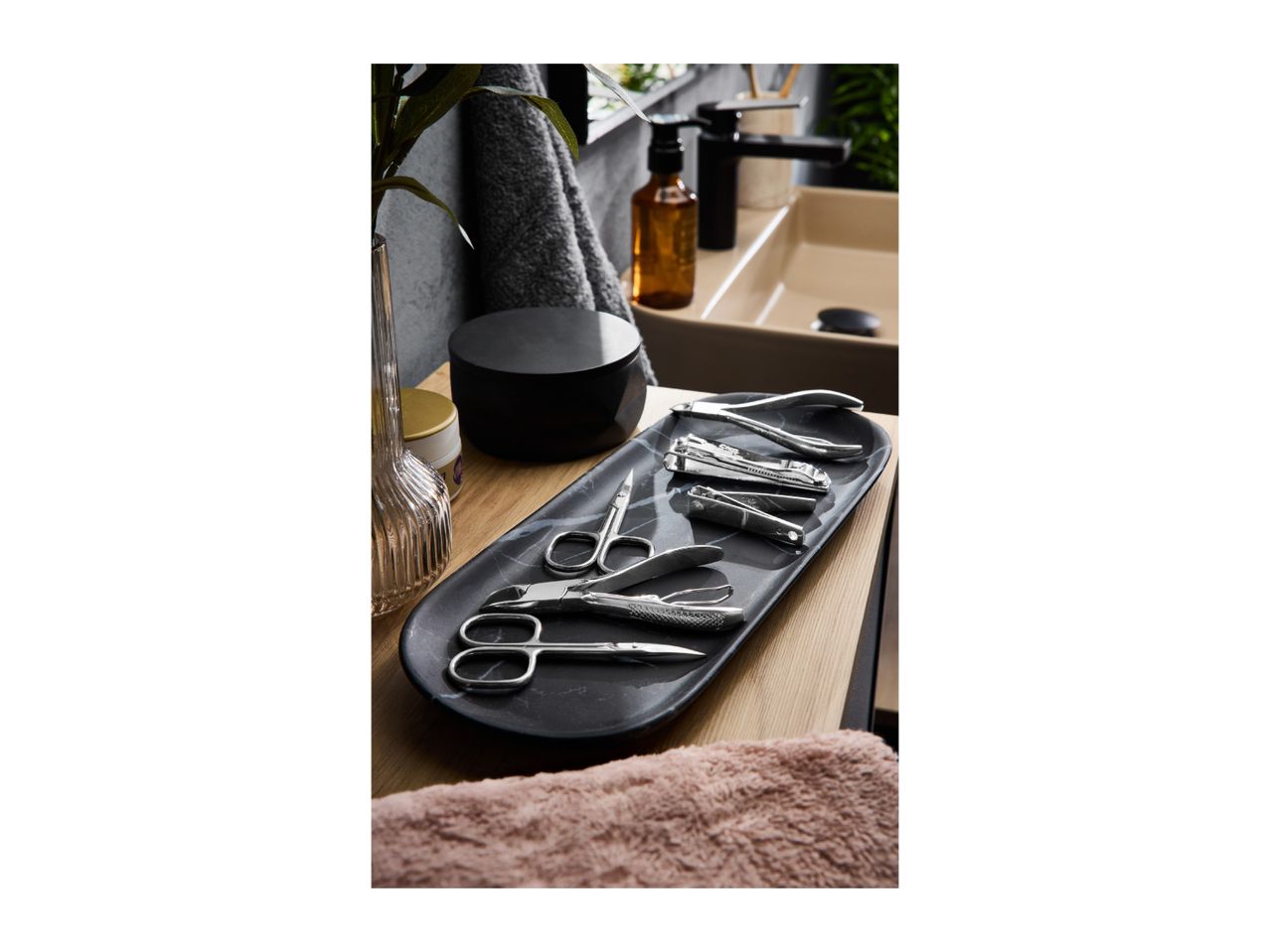 Manicure set on a marble tray, with a sink and toiletries in the background.