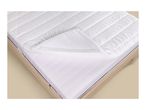 White quilted mattress topper with elastic corner straps on a wooden bed frame