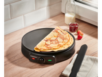 SILVERCREST® crêpemaker met crêpes, jam en aardbeien op een houten aanrecht.
