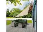 Triangular shade sail and wicker patio furniture with green cushions.